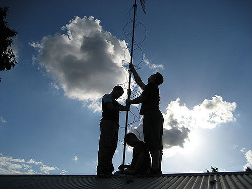Community members raising an antenna on the roof of a shed in suburban south australia